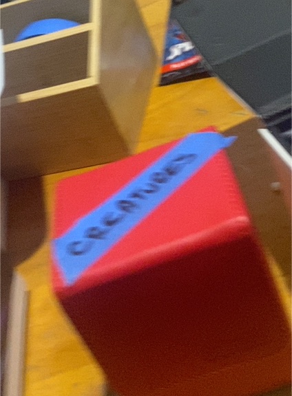 Red Cube with Blue Tape Marked 'CREATURES' — front
