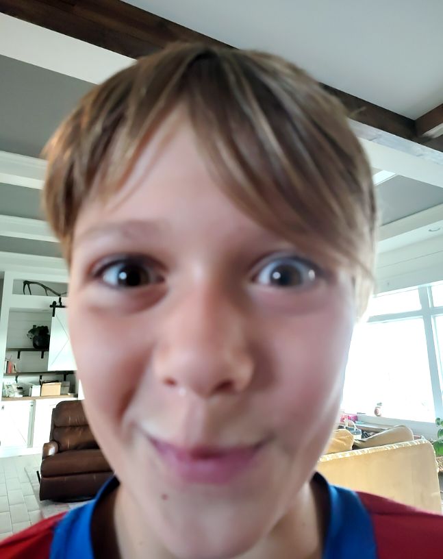 Close-up photo of a young boy indoors — front